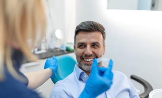Patient smiling at dentist holding clear aligner