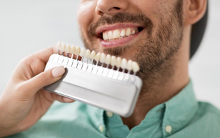 Dentist placing shades of porcelain next to patient's smile