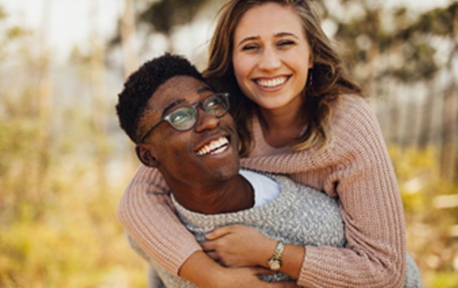 Smiling boyfriend giving girlfriend a piggy-back ride outside