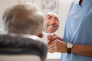 a person admiring their smile in a handheld mirror